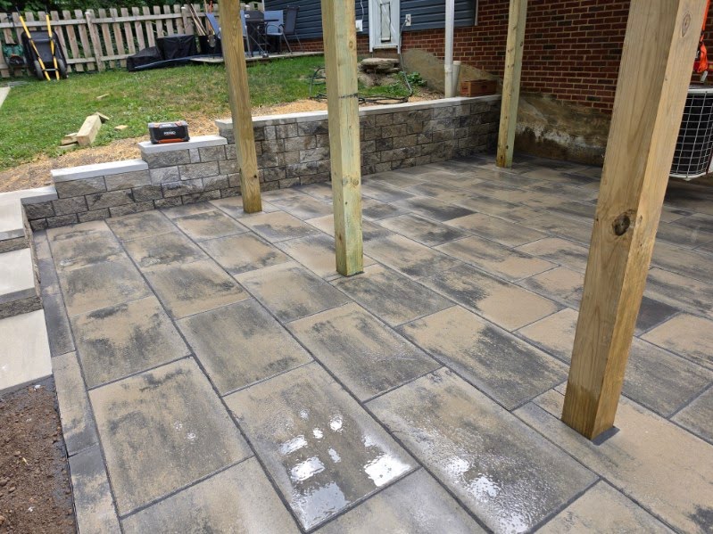 Large-format slab paver patio with stone seat wall and pergola posts